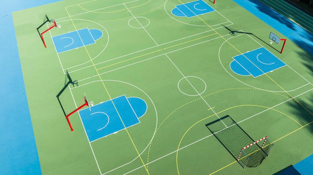 Luftaufnahme eines multifunktionalen Sportplatzes mit Basketball- und Handballfeld in Grün und Blau