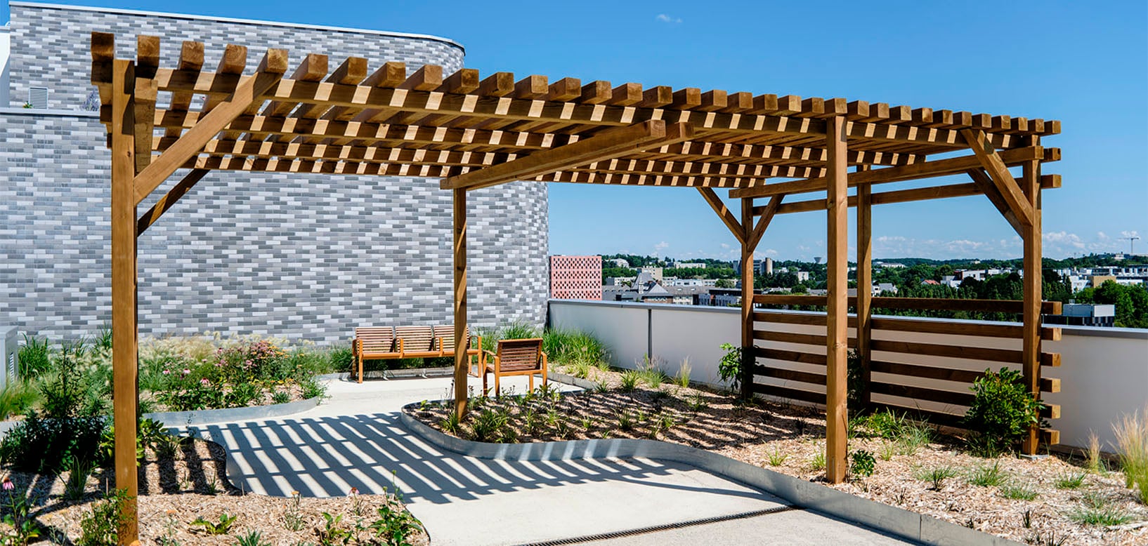 Holzpergola auf Dachterrasse mit Sitzbereich, Gräsern und Stauden, Stadtpanorama im Hintergrund
