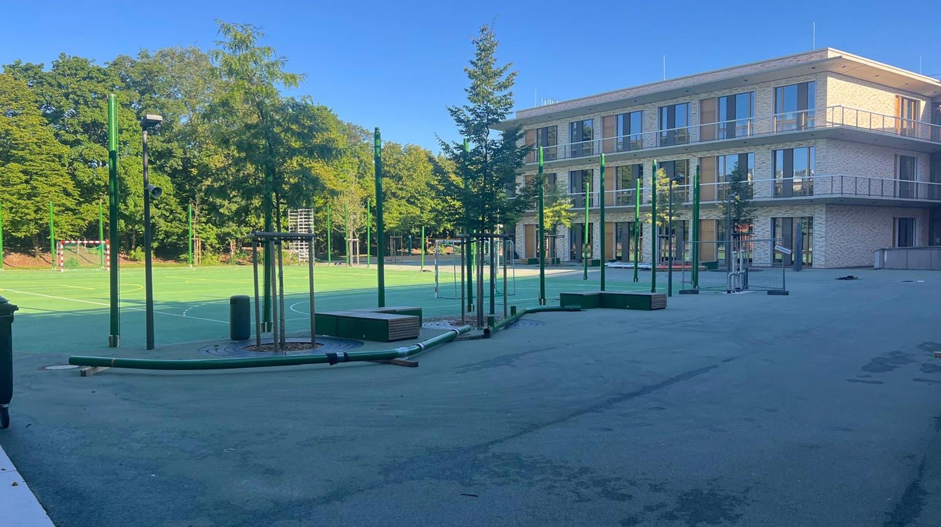 Schulhof des Bildungscampus Strehleranger mit grünen Sportanlagen, Klettergerüsten und modernem Schulgebäude