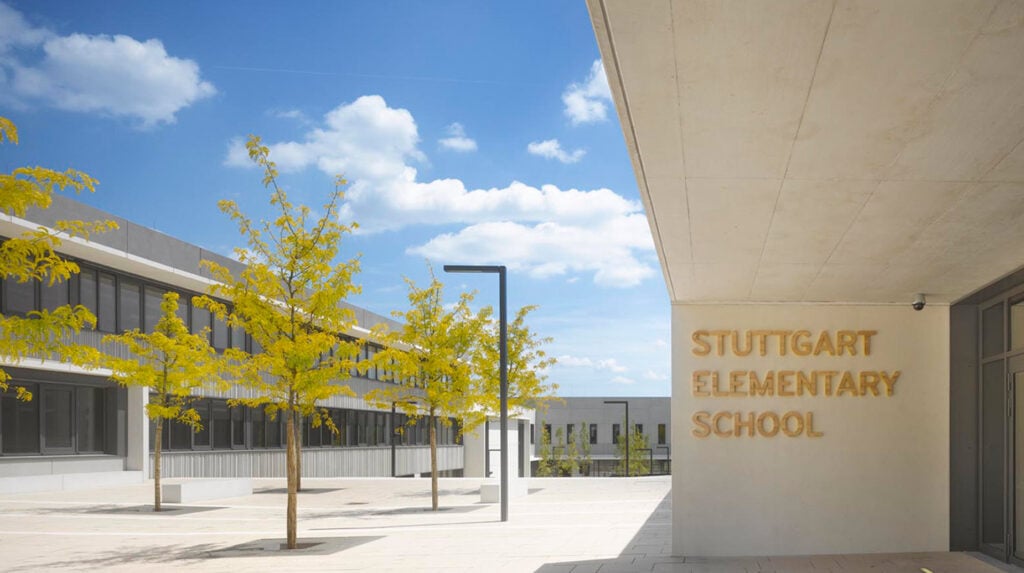Außenanlage der Stuttgart Elementary School in Böblingen mit modernem Schulgebäude und jungen Bäumen im Innenhof